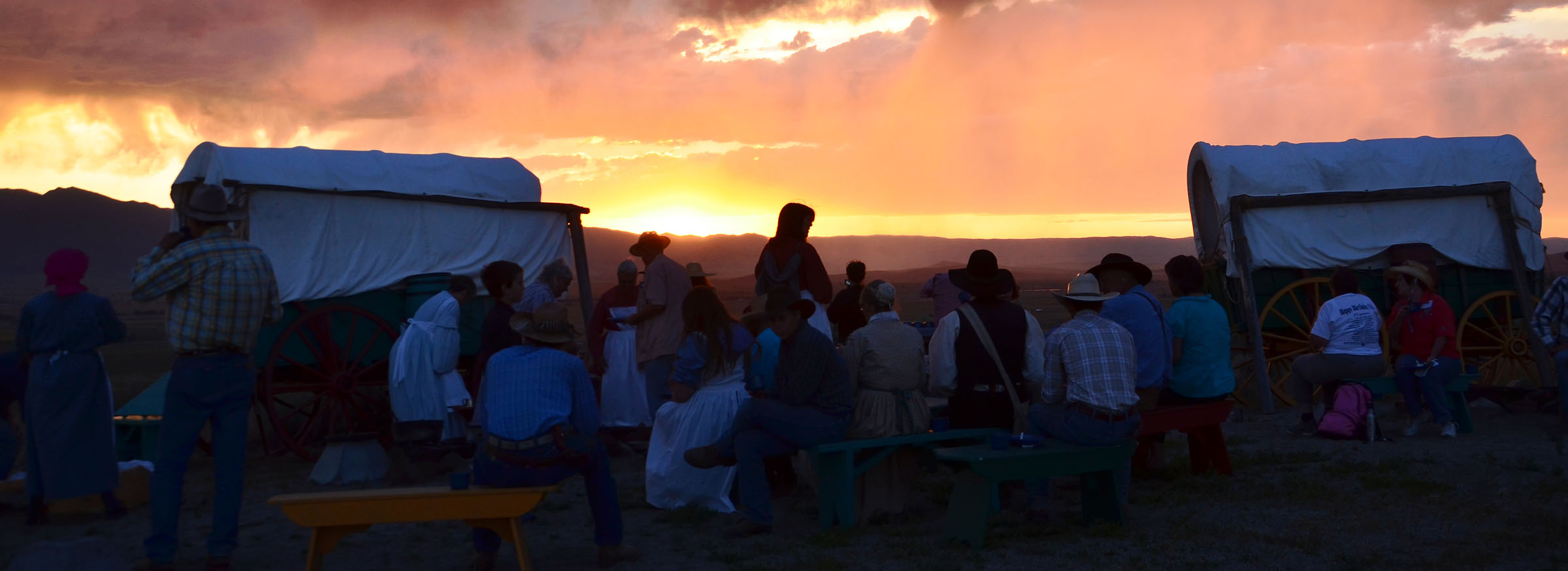 Sunsetting behind a covered wagon and a small crowd of visitors at the Oregon trail Interpretive Center